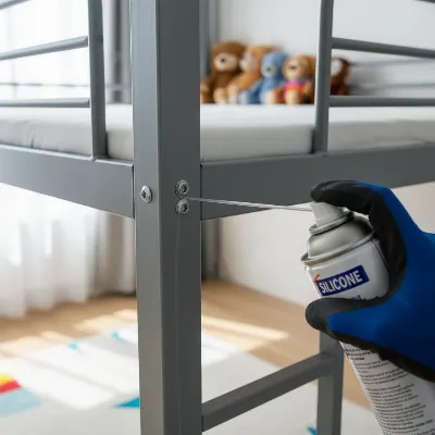 Expert applying metal-safe lubricant to a squeaky metal bunk bed joint.